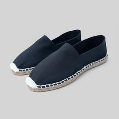 Pair of navy blue espadrilles with white trim on a white background