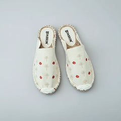Pair of white slippers with red floral patterns on a white background