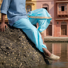 Person wearing light blue pants sitting on a rocky surface.