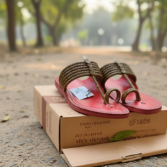 Red sandal with brown rope details and a visible brand tag on a blurred background