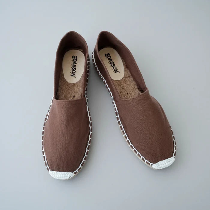 Pair of brown espadrilles with white trim on a white background