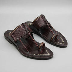 Pair of brown sandals with decorative straps on a gray background