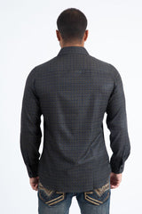 Man wearing a black and multi color long sleeve geometric print button-down shirt paired with jeans, modern men's fashion look